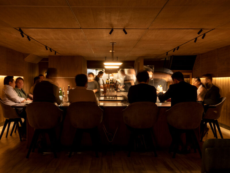 Interior elegante de restaurante japonês com balcão de madeira e iluminação intimista